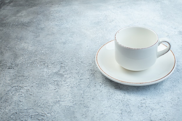 Elegant empty white cup and sauce on the left side on isolated gray surface with distressed surface