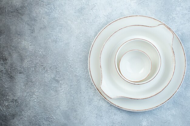 Элегантный пустой белый сервиз для ужина слева на изолированной серой поверхности со свободным пространством