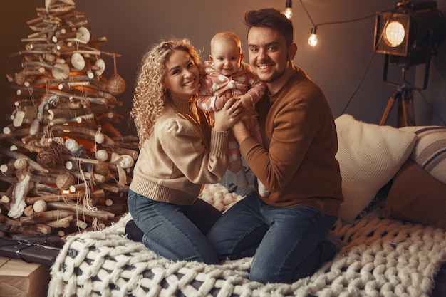 Elegante famiglia seduta a casa vicino all'albero di natale