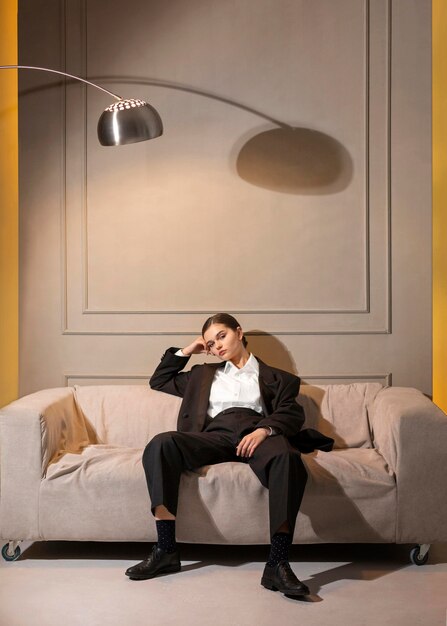 Elegant female model posing in a sofa in jacket suit. new feminity concept