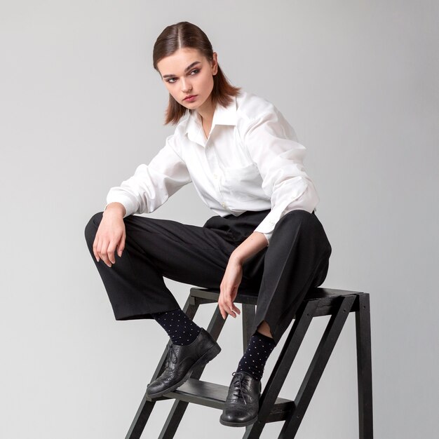 Элегантная женская модель позирует на лестнице в пиджаке. новая концепция женственности