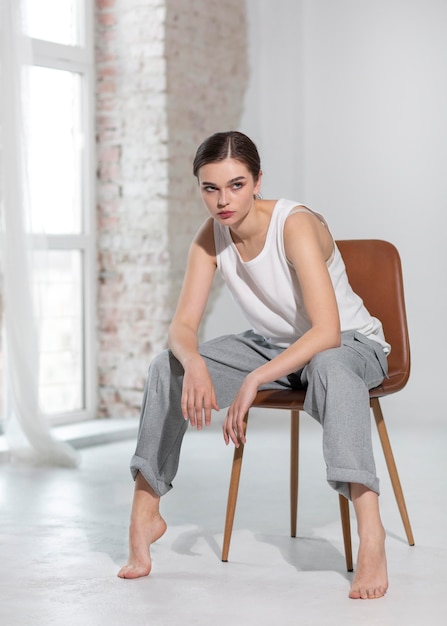 Elegant female model posing in tank top and grey trousers in a bright studio . new feminity concept