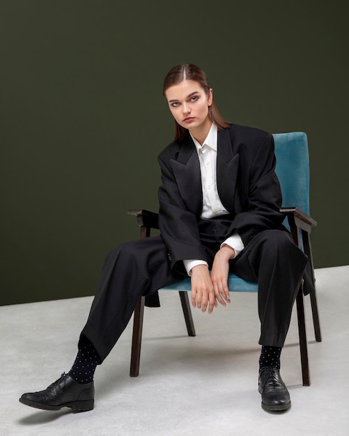 ジャケットスーツの肘掛け椅子に座っているエレガントな女性モデル。新しい女性らしさの概念