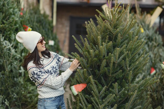 Elegant girl buys a Christmas tree.