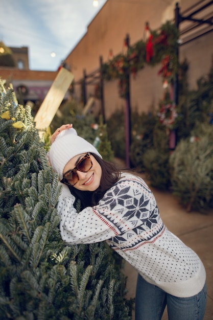 Elegant girl buys a Christmas tree.