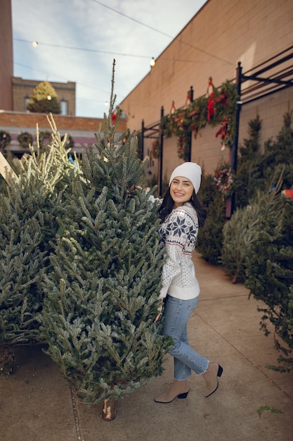 Elegant girl buys a Christmas tree.