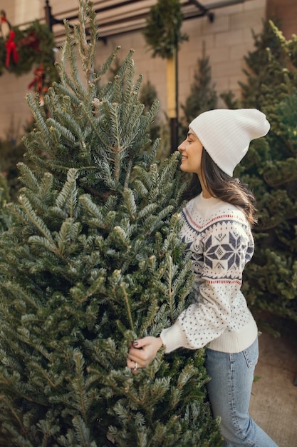 Elegant girl buys a Christmas tree.