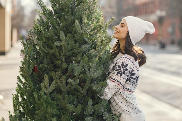 エレガントな女の子がクリスマスツリーを購入します。