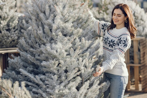 Elegant girl buys a Christmas tree.