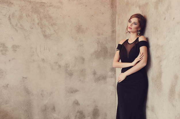 Foto gratuita donna elegante e glamour con abito nero in posa, concetto di moda