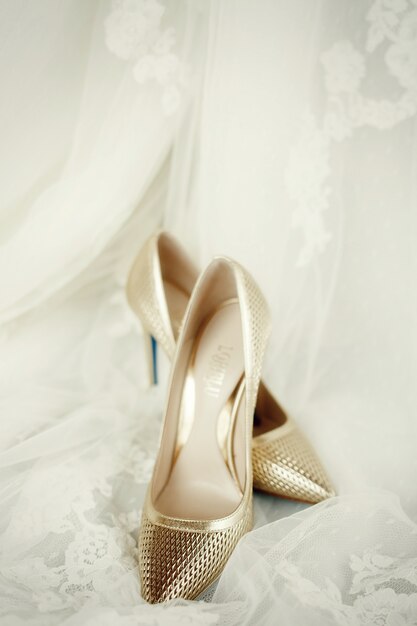 Elegant golden shoes stand on lace wedding veil 