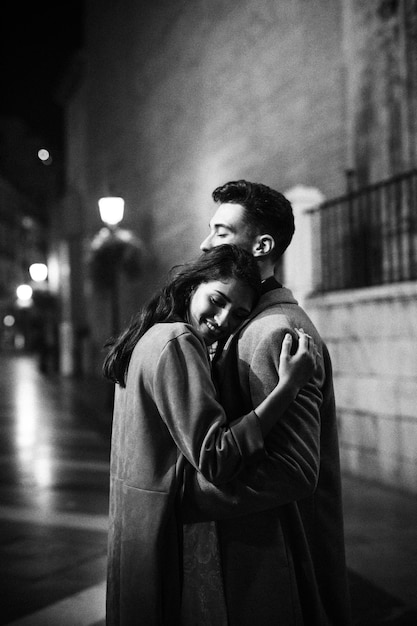 Elegant happy woman hugging with young man on street at night