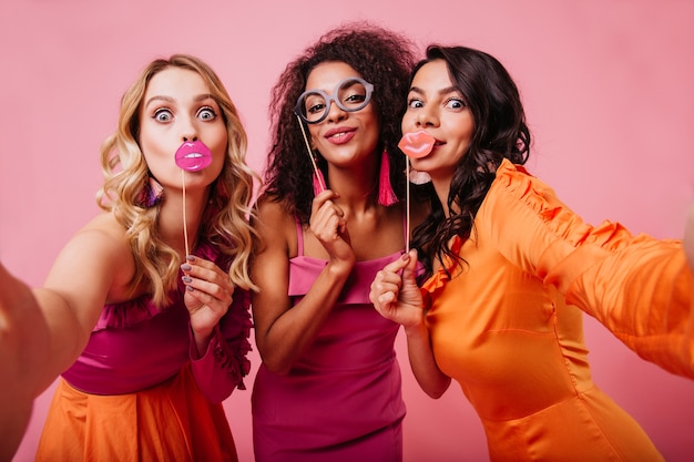 Free photo elegant ladies making faces on pink wall