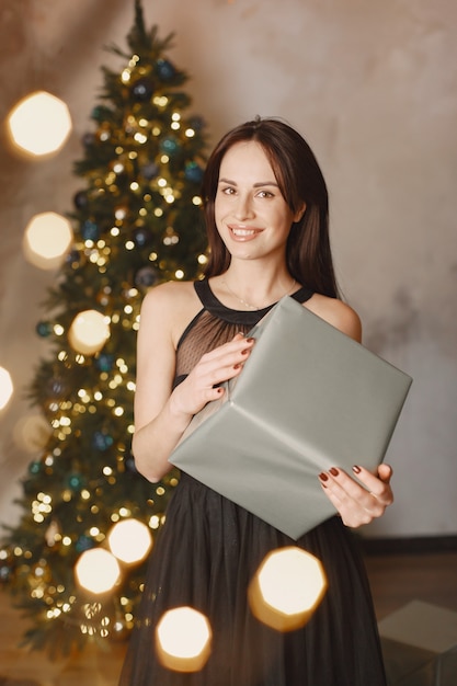 Elegant lady near Christmas tree.