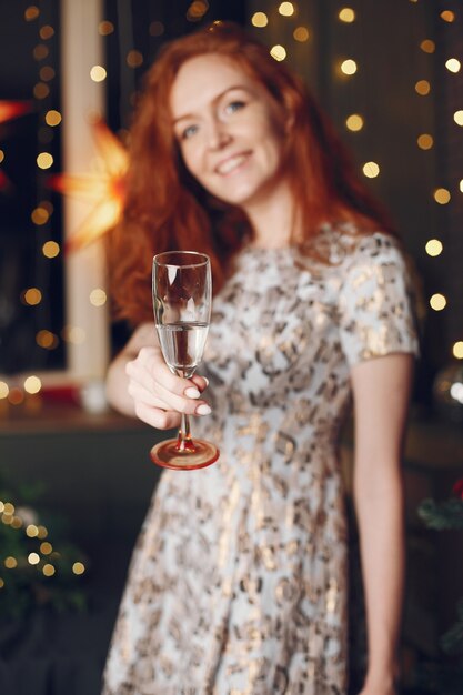 クリスマスの木の近くのエレガントな女性。シャンパンで家にいる女性。