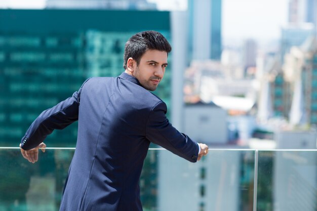 Elegant man leaning on a railing looking back