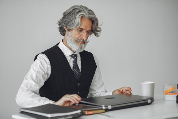 Элегантный мужчина в офисе. Бизнесмен в белой рубашке. Человек работает с ноутбуком.