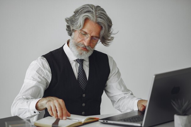 사무실에서 우아한 남자입니다. 흰 셔츠에 사업가입니다. 남자는 노트북과 함께 작동합니다.