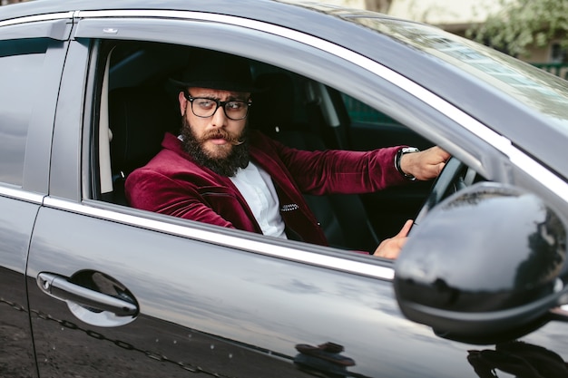 Foto gratuita uomo elegante seduto nella sua auto