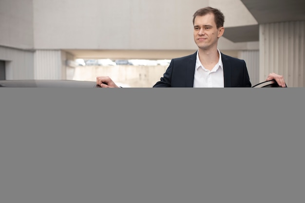 Free photo elegant man standing next to his car for taxi services