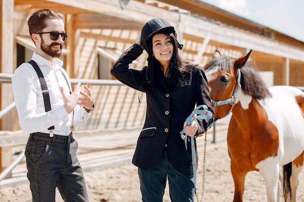 Элегантный мужчина стоит рядом с лошадью на ранчо с девушкой