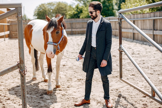 Elegant man standing next to horse in a ranch