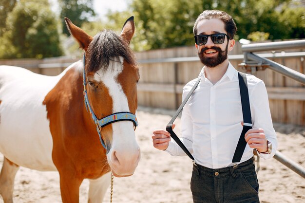 Elegant man standing next to horse in a ranch