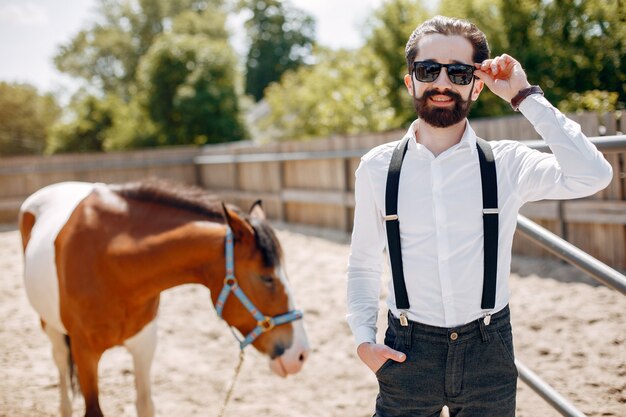 Elegant man standing next to horse in a ranch