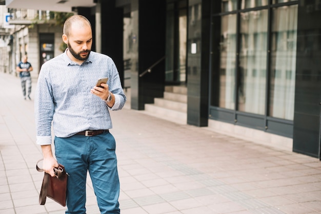 elegant man walking down street with smartphone