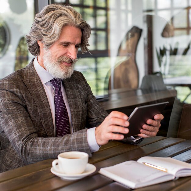Elegant mature male holding tablet at the office