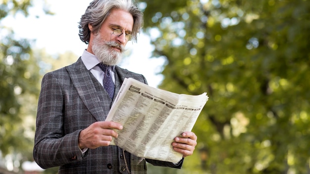 Free photo elegant mature male reading newspaper