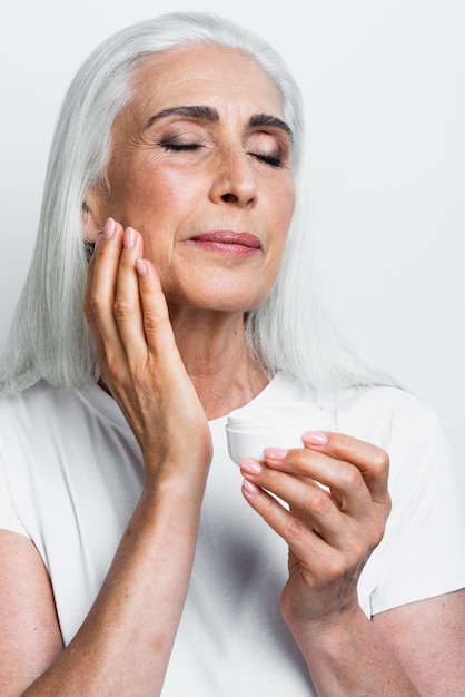 Elegant mature woman applying moisturizer