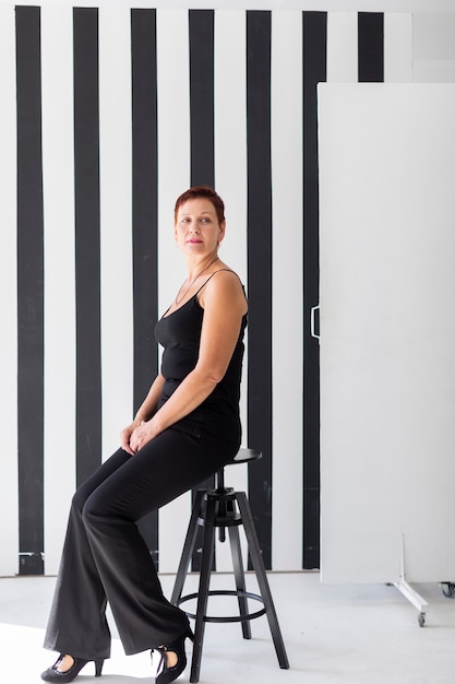 Elegant mature woman sitting on a stool