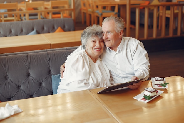 Elegant old couple in a cafe using a tablet