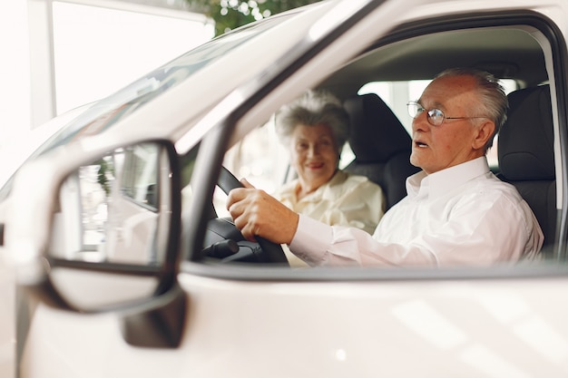 Free photo elegant old couple in a car salon