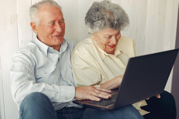 Free photo elegant old couple sitting at home and using a laptop