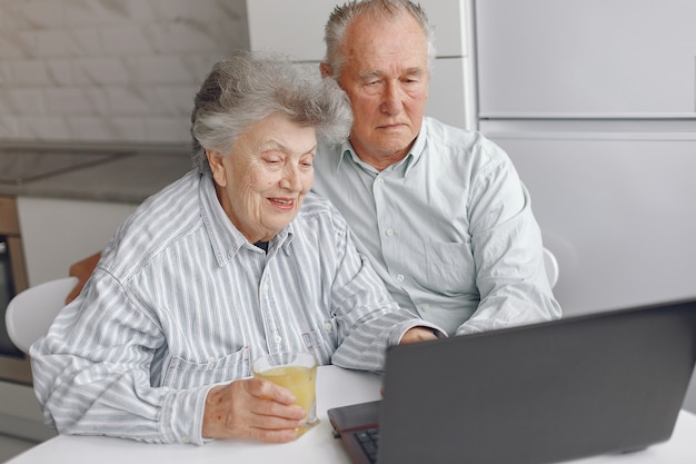 Foto gratuita vecchie coppie eleganti che si siedono a casa e che per mezzo di un computer portatile
