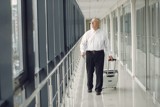 Elegant old man at the airport with a suitcase