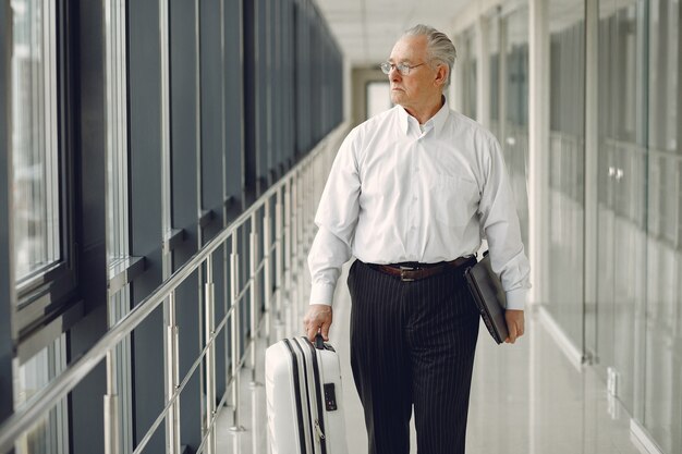 Elegant old man at the airport with a suitcase