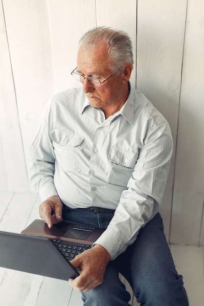 Elegant old man sitting at home and using a laptop