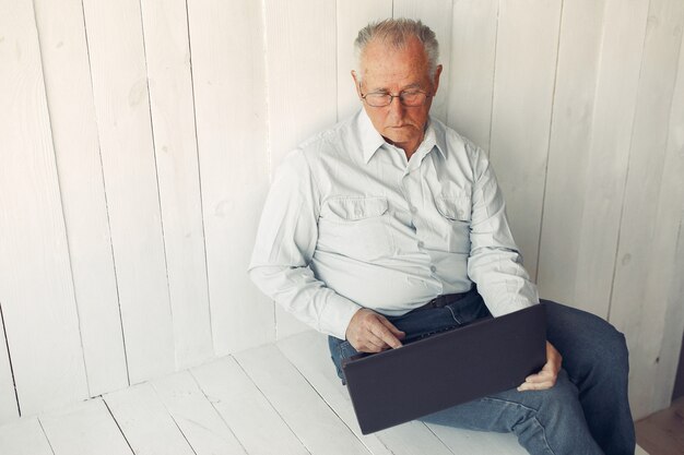 Elegant old man sitting at home and using a laptop