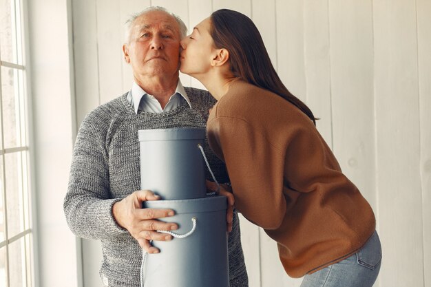 Elegant old man standing at home with his granddaughter