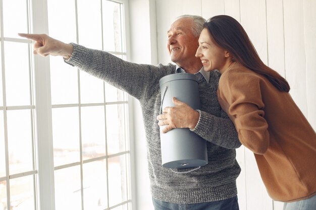 Elegant old man standing at home with his granddaughter