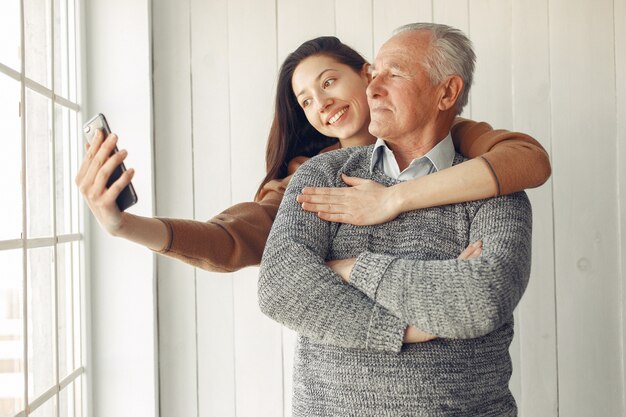 Elegant old man standing at home with his granddaughter