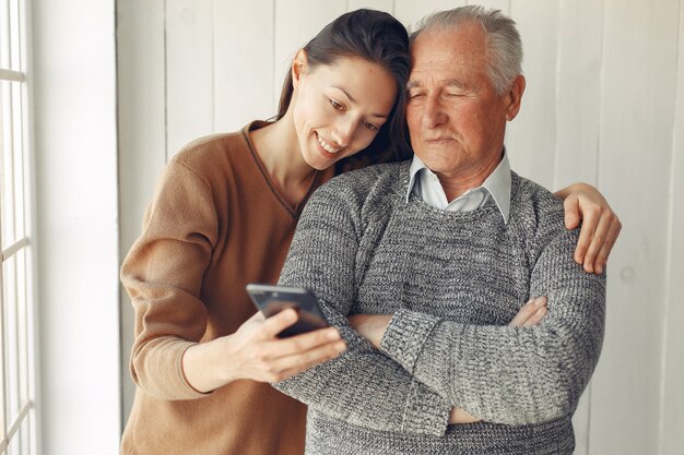 Elegant old man standing at home with his granddaughter