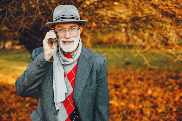 Foto gratuita elegante vecchio in un parco soleggiato autunno