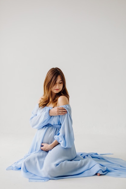 Elegant pregnant mom in dress posing in proud of her pregnancy