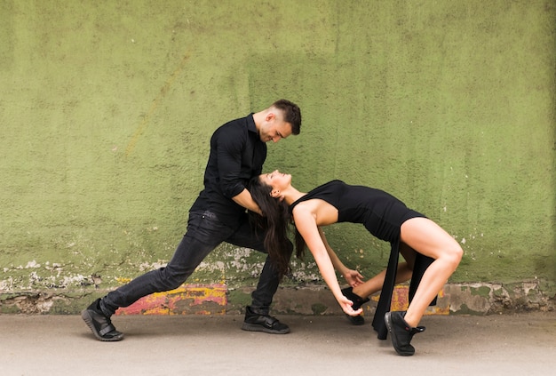 Free photo elegant romantic couple dancing against old green wall