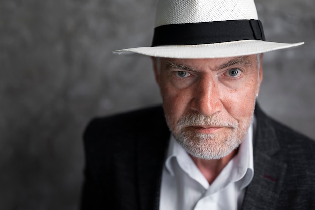 Free photo elegant senior man posing in suit and hat