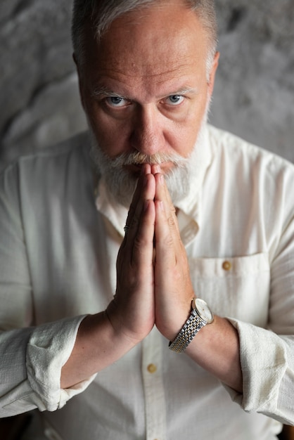 Free photo elegant senior man in white shirt praying